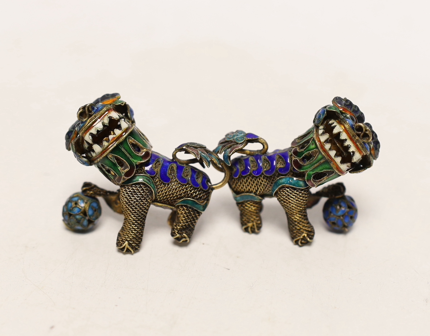 A pair of Chinese? gilt white metal and enamel Shi Shi, length 45mm.